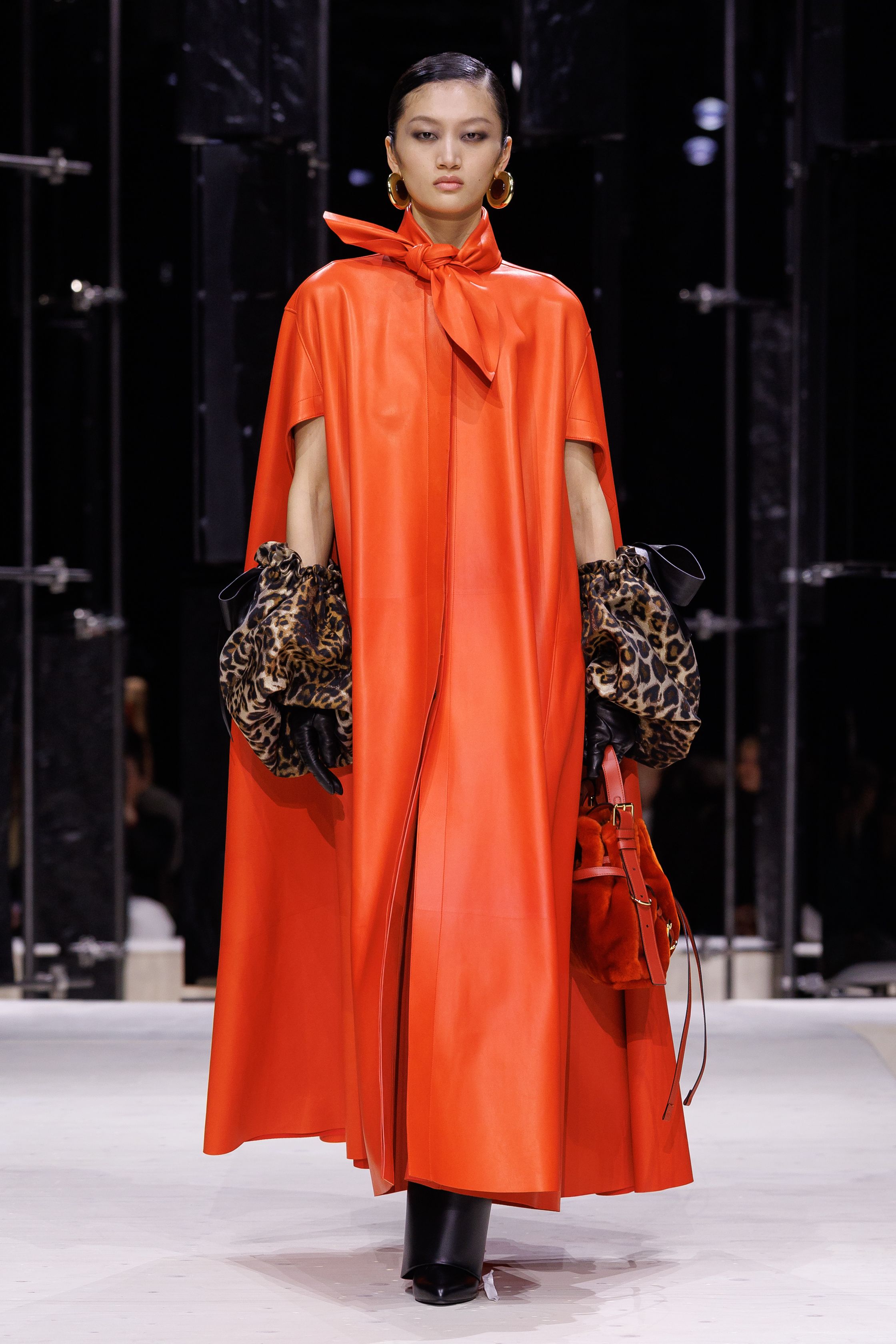 Givenchy 2026秋冬在现代建筑空间中呈现一场充满戏剧性的时装叙事：雕塑式西装、亮色斗篷、结构礼服与夸张装饰共同构建品牌标志性的高级时装气质。蓝色、红色与黄色的高饱和色彩与黑白经典形成鲜明对比，服装通过立体剪裁与夸张廓形展现出强烈视觉张力。整场系列在优雅与戏剧之间取得平衡，展现现代高级时装的力量-顽石频道趋势研究